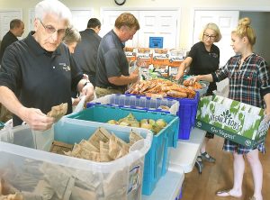 Volunteers fill backpacks for for Mon County schools snack program
